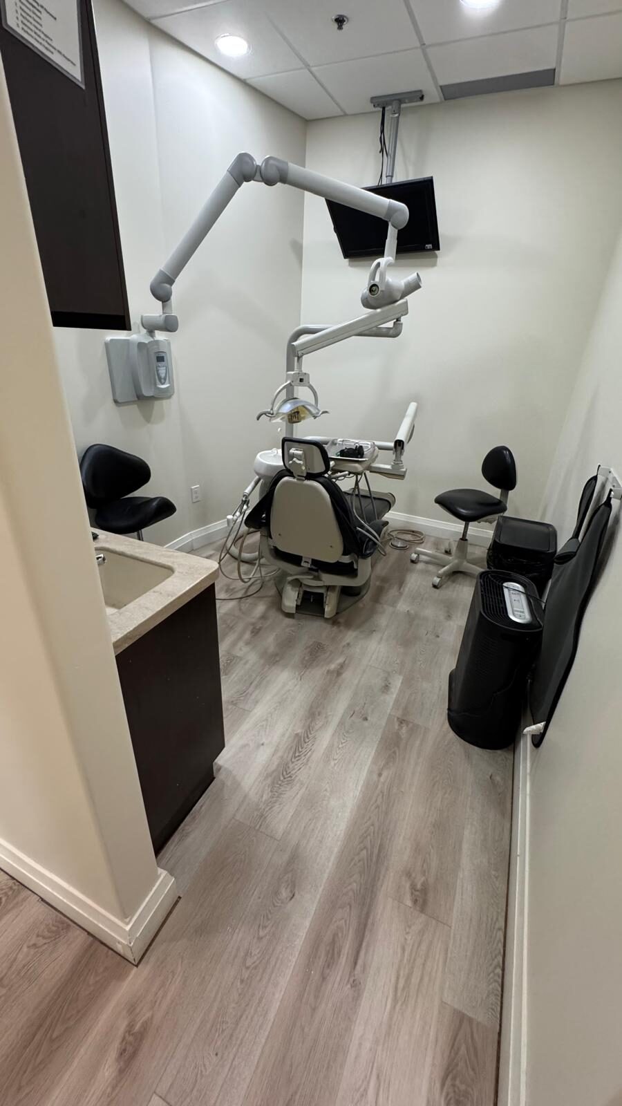 A refreshed operatory: new light wood-look flooring throughout and a wall-mounted display for the clinical team.