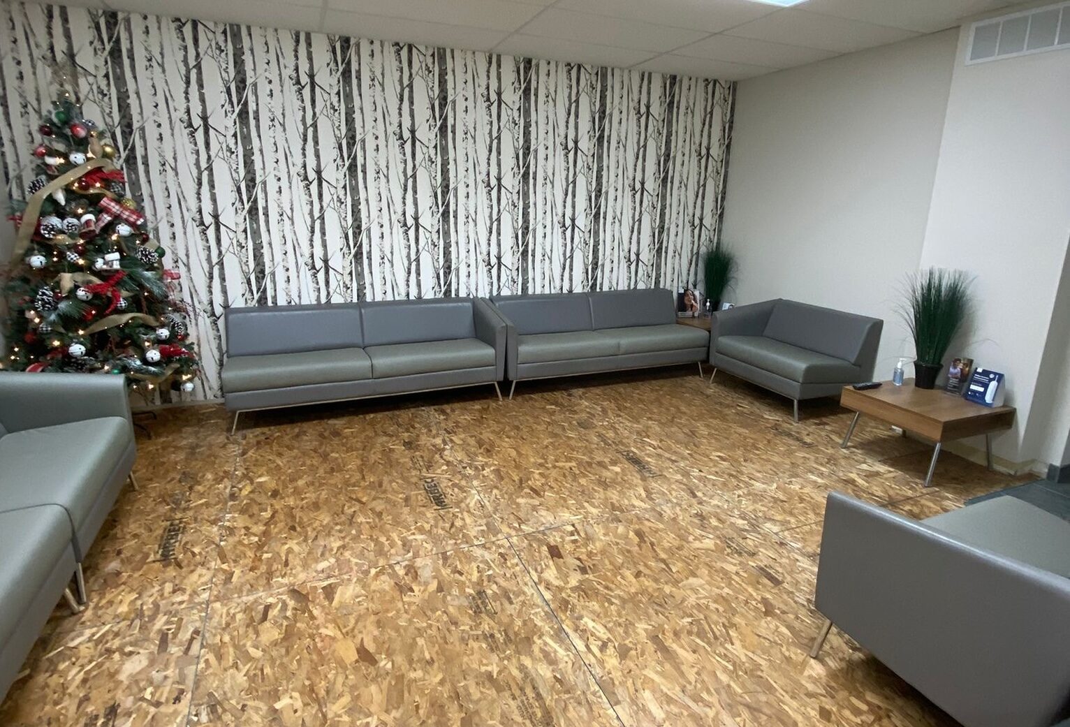 The waiting area on bare subfloor mid-project, furniture shifted for the overnight work.