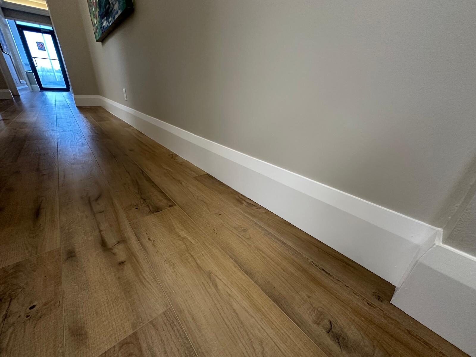 New wood-look LVT and fresh baseboards in a finished hallway.
