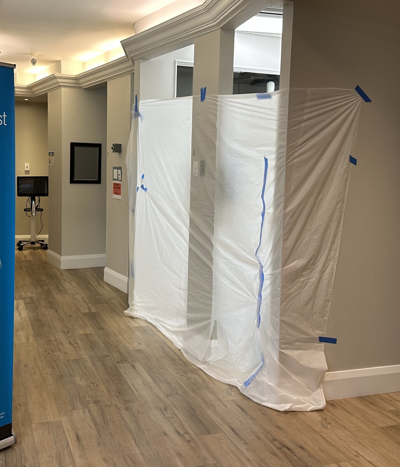 A temporary plastic dust barrier sealing the work zone while keeping rest of clinic operational.
