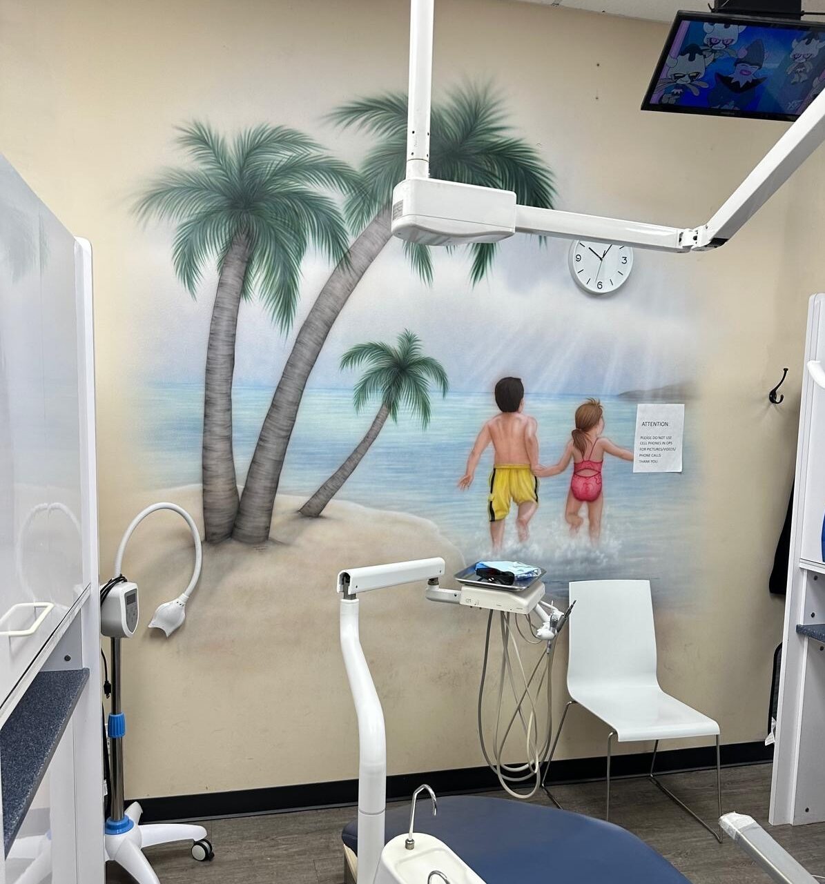 An operatory before the work, with a dated painted beach mural.