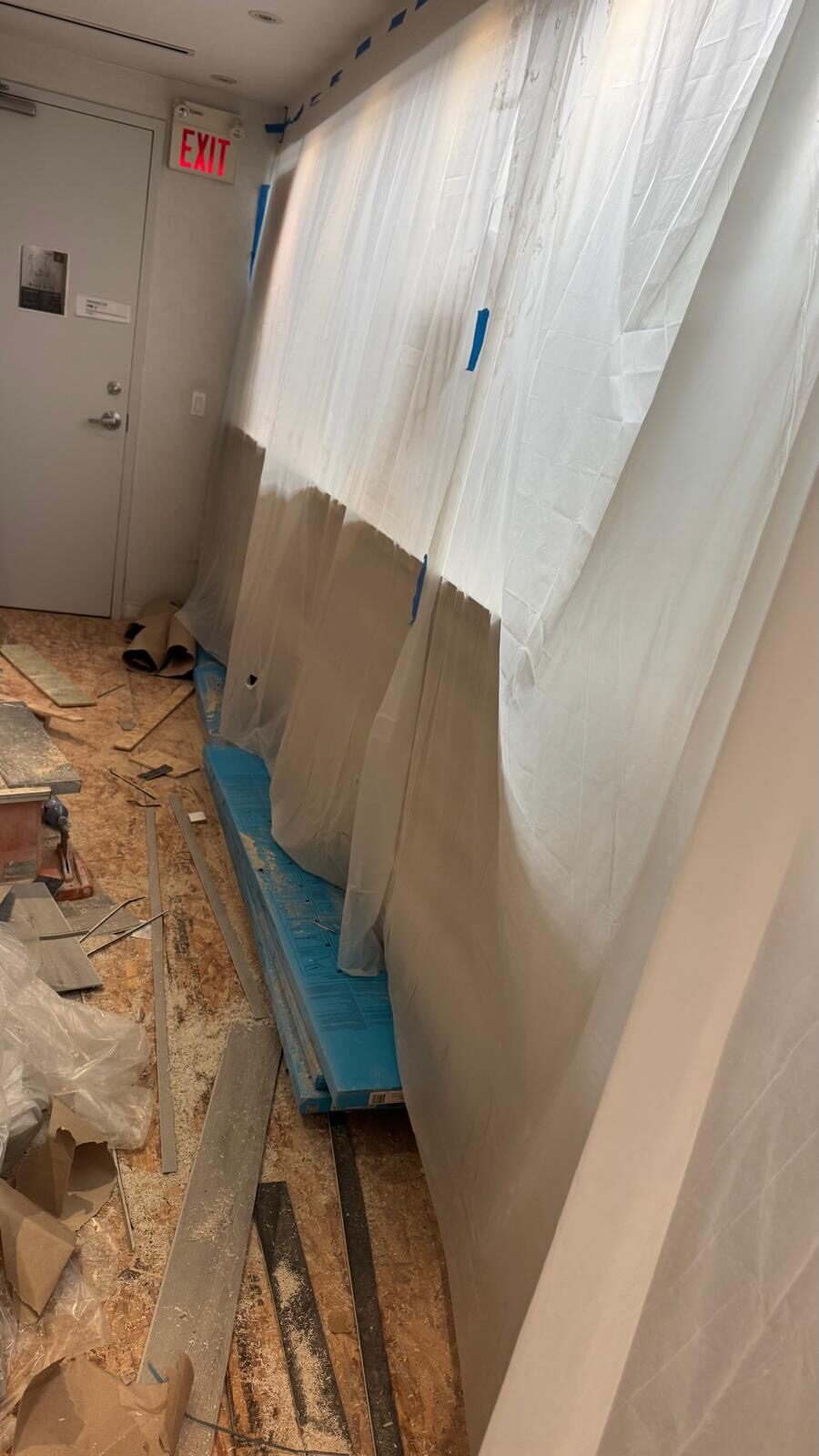 Old flooring being torn out behind protective sheeting.