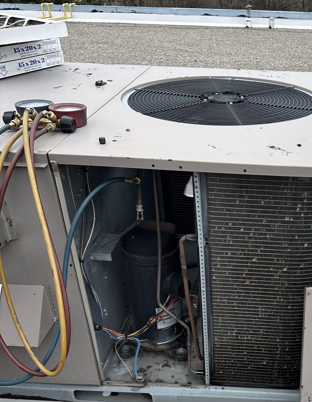 Servicing an HVAC condenser unit with coils and refrigerant lines exposed.