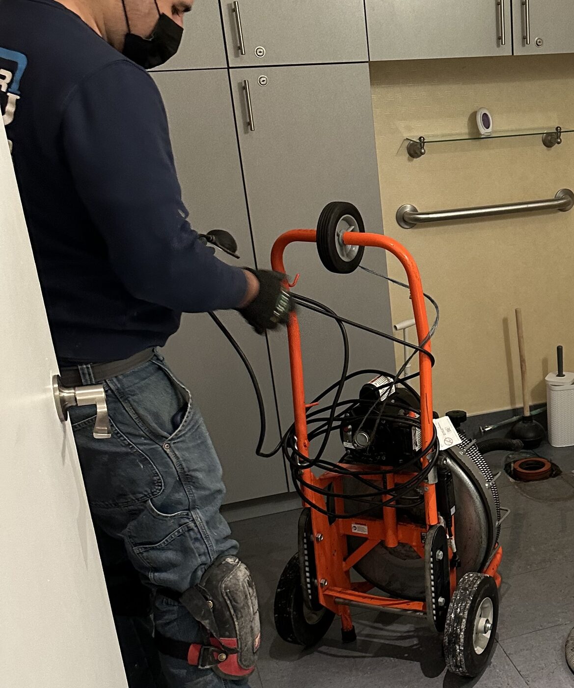 Clearing a clinic drain line with a powered auger.
